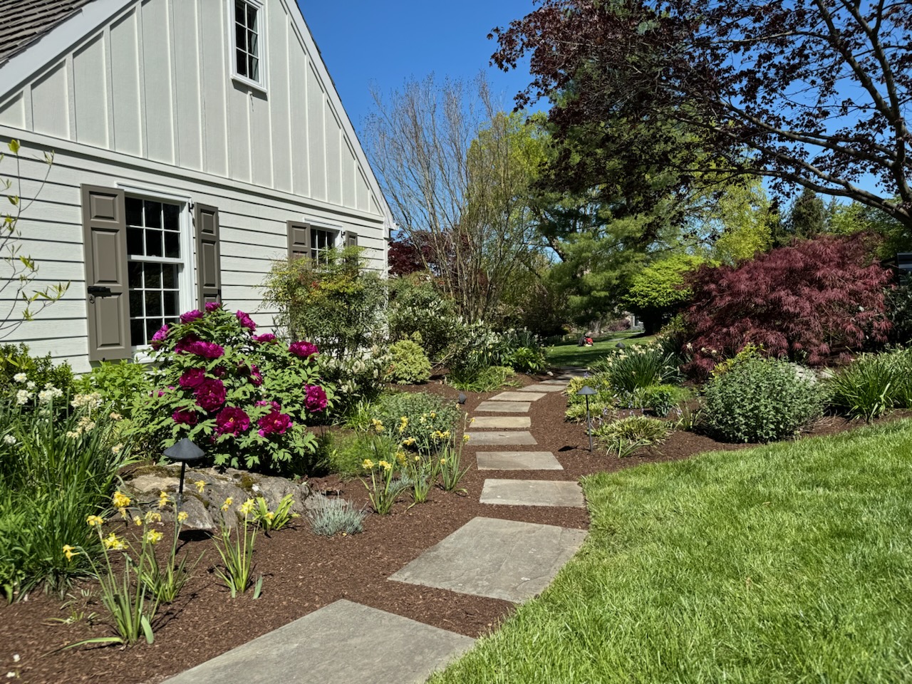 Lush flower beds and stone walkway alongside a suburban home